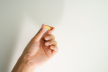 Male hand holding Fish oil capsules with omega 3, omega 9, vitamin D, vitamin E, Cod liver oil