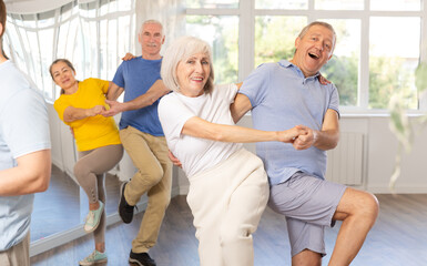 Couple of elderly man and elderly woman dancing twist in studio
