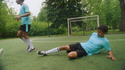 Three diverse teenage soccer players battling for control of ball, one sliding in defensively as two others maneuvering on lush outdoor field during competitive practice session - Powered by Adobe