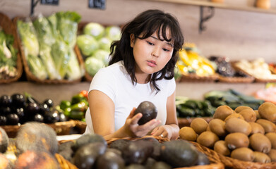 Asian positive girl choosing fruits in supermarket