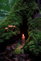 witch amulet and burning wax candle in mystery dark forest, abstract nature background. magical candle for witchcraft, esoteric ritual. mysterious fairy tale scene