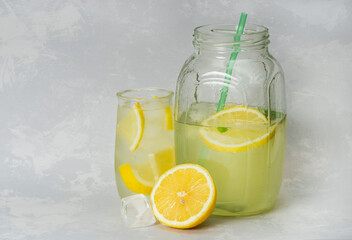 Homemade lemonade with lemon and mint in a glass jar and glass on a gray background. A refreshing summer drink. Ingredients for lemonade