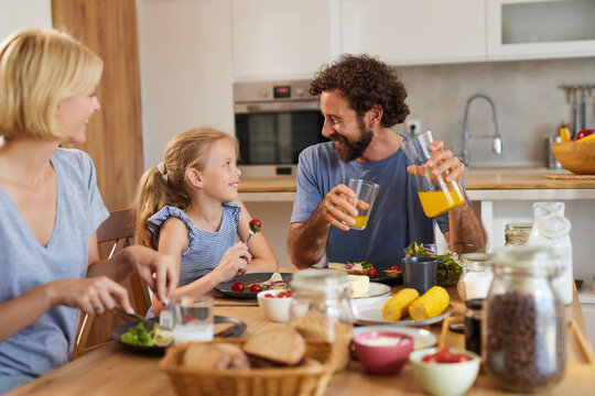A family gathers around the dining table, sharing food and laughter. Fresh ingredients are present, highlighting a joyful atmosphere filled with love and togetherness. - Powered by Adobe
