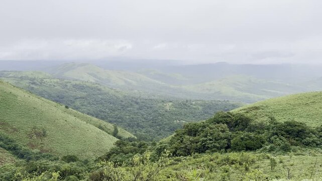 Rolling green mountains of Devarmane, Malnad, Karnataka during monsoon. Rain clouds sweep swiftly overhead, capturing the serene and dramatic beauty of the Western Ghats.