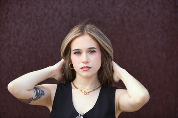 Portrait of blonde woman with light eyes, young and beautiful, touching her hair with both hands...
