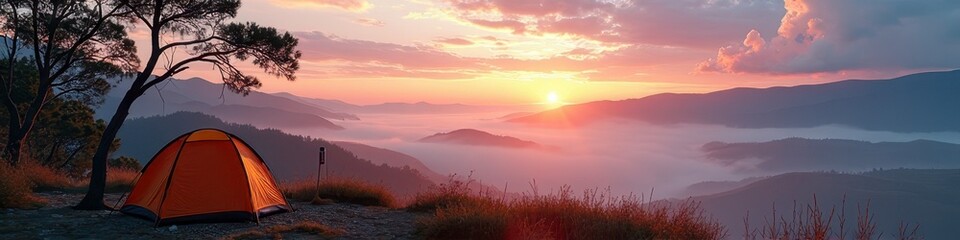 Obraz premium Sunset over mountain valley with orange tent and misty clouds