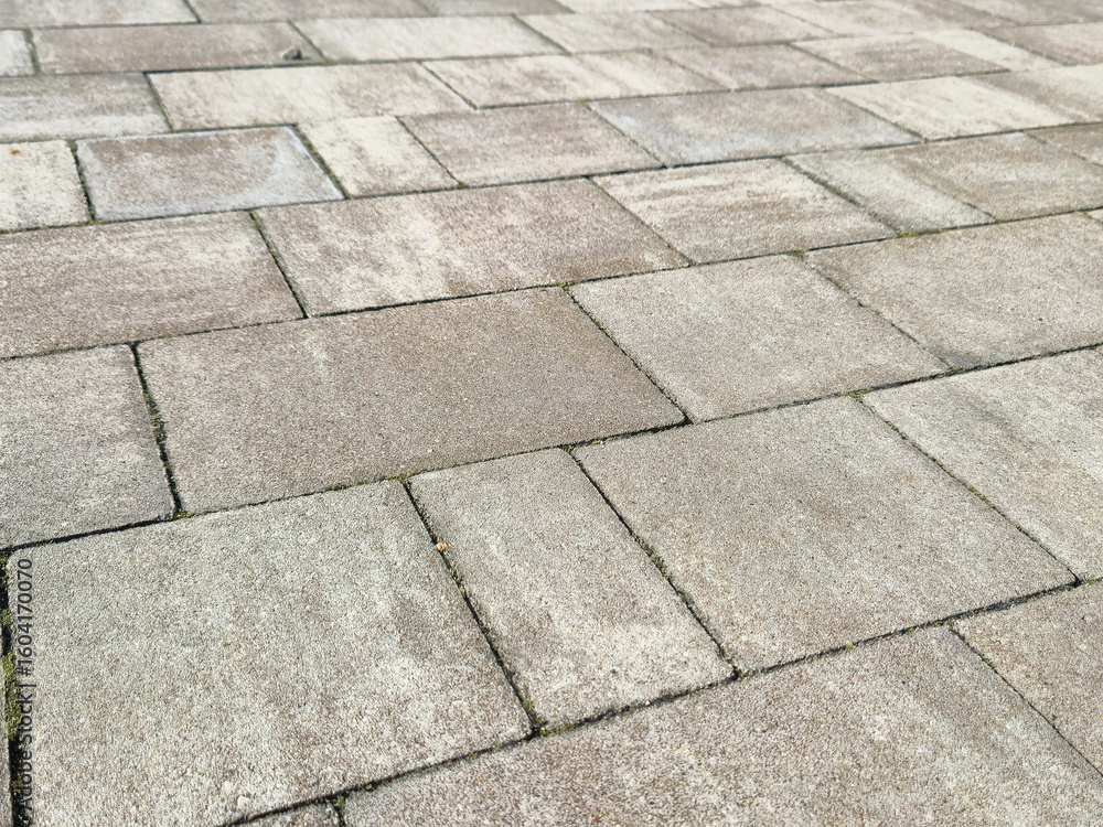 Poster close-up view of textured paving stones on a walkway, showcasing their uniform design and subtle col