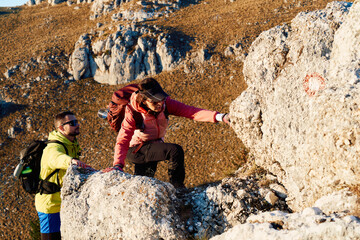 A fit and adventurous couple helps each other climb to the mountain summit during a breathtaking...