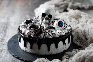 Spooky Halloween chocolate Cake with Skull, Eyeball, and Spider Decoration on wooden table