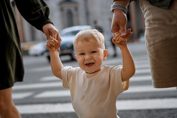 mother and father holding hands of baby boy crossing road on zebra crossing