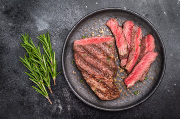 Grilled New York Striploin steak, perfectly seared with beautiful grill marks, showcasing its juicy tenderness and rich flavor. black background. top view