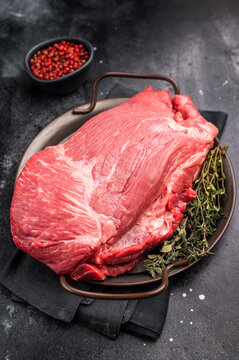 Raw Top Round beef meat cut, topside with hrebs for roast. black background. Top view