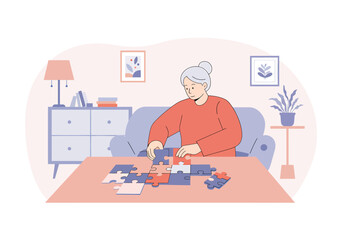 An elderly woman with grey hair sits at a table in her living room, assembling a jigsaw puzzle as a hobby.