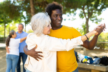 Happy cheerful positive smiling adult friends dancing pair dance in garden