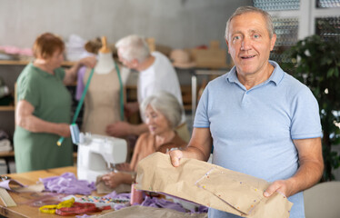 Elderly male student with sewn pattern at sewing master class
