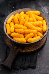Deliciously addictive cheese flavored corn puffs, beautifully arranged on a plate. black...
