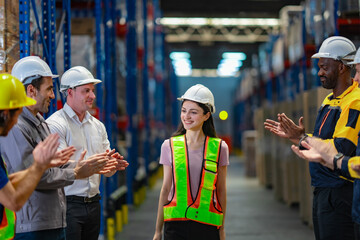 A diverse warehouse team claps to celebrate a female worker’s achievement. The image reflects recognition, success, and teamwork in a modern logistics workplace.