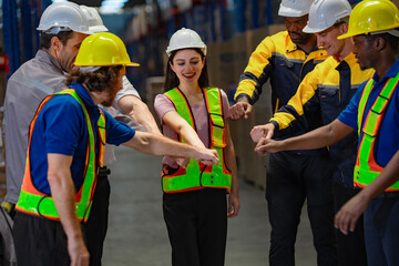 Warehouse crew gathers with hands together in solidarity before starting operations. Represents...