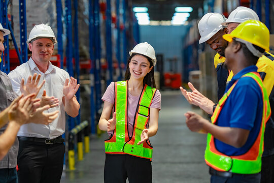 Smiling female staff member receives public recognition from her diverse team, celebrating her recent promotion in a supportive and inclusive workplace.