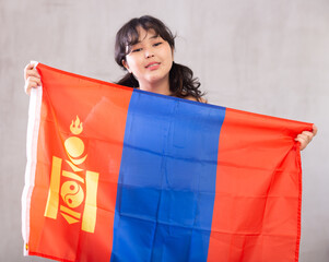 Portrait of smiling young asian girl in casual clothes holding Mongolian flag in studio