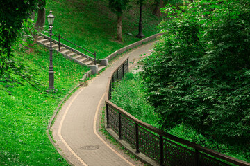 park outdoor scenery walking site paved road track curved shape in green trees and grass hills...