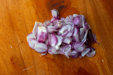 Pile of sliced shallot on a solid wooden cutting board, shot with shallow depth of field
