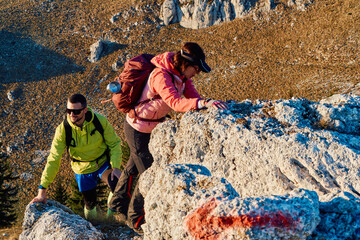 A fit and adventurous couple helps each other climb to the mountain summit during a breathtaking...