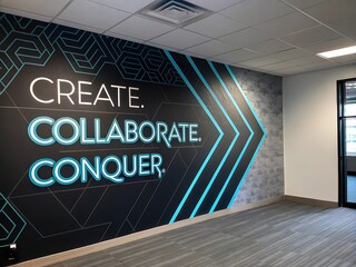 Modern office interior with inspiring motivational wall art featuring create collaborate conquer text