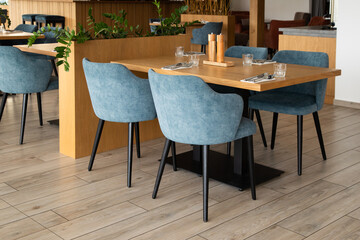 A welcoming view of a modern restaurant's dining section, featuring a set wooden table surrounded by comfortable blue chairs