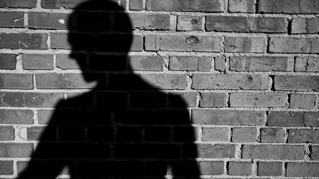 Shadow figure lurking by brick wall