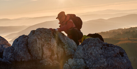 A fit and adventurous couple helps each other climb to the mountain summit during a breathtaking...