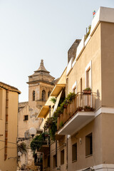 Mediterranean balconies and church tower in narrow street of Mazara del Vallo