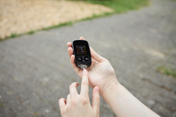 A woman measures her blood sugar level on the street using a glucometer. The concept of diabetes,
self-monitoring and health care outside the home.