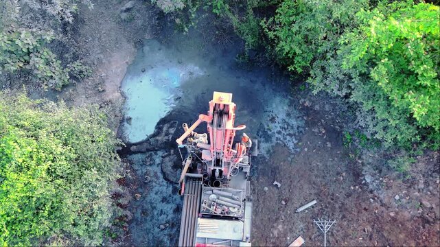 Drone shot borewell drilling amid forest canopy