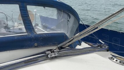 A sailing yacht main sheet and traveller controlling the mainsail as the boat runs downwind in light airs. The mainsheet is attached to the book and controls the angle of the sail to the wind