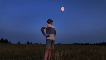 Naklejka premium Amateur astronomer watching stars, Moon, planets and other celestial objects from a field in nature.