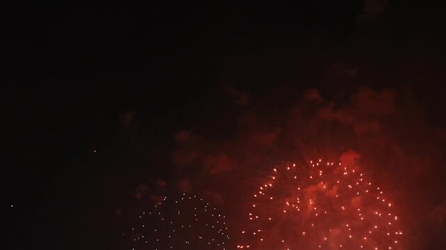Close-up view of several bursts of vibrant red fireworks illuminating the dark night sky