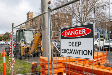 A safety warning sign reading “Danger – Deep Excavation” on a temporary fence at a...
