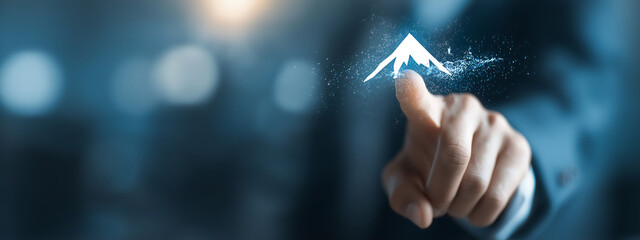 Businessman touching screen with mountain peak and flag icon, blurred office background