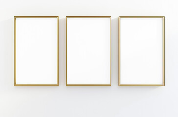 Minimalist interior mockup with three vertical gold picture frames aligned on a white wall, perfect for showcasing artwork or posters