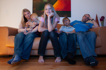 Family Life, Chick Flick. A teenage girl enjoying watching TV with her bored family behind on the...