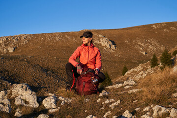 A female hiker unpacks her gear and relaxes after a challenging day of mountain trekking, enjoying...
