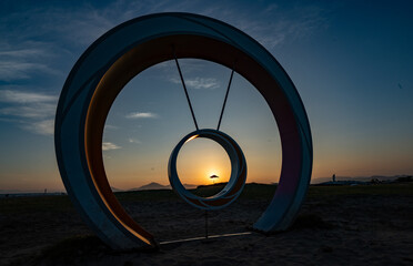 A beautiful beach sunset landscape with a silhouette of a parasol on the sand.