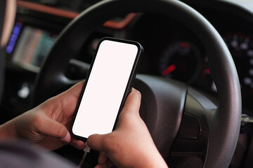 Person holding a smartphone with a blank white screen inside a car. Mockup for a mobile app or GPS...