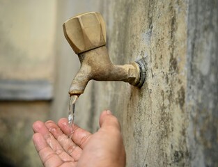 Illustration of clean water usage. Water flows from an old faucet into the palm of your hand.