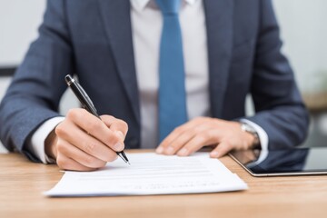 Business professional reviews documents and takes notes at a modern workspace