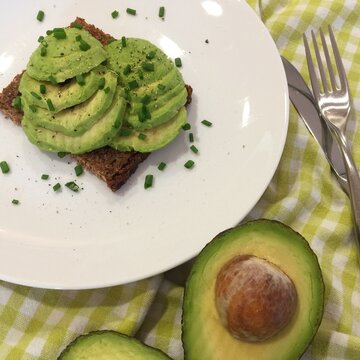 Close-up overhead view of Sliced avocado with chives on a slice of rye bread