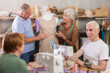 Group of elderly men and women sew and work with mannequin during master class