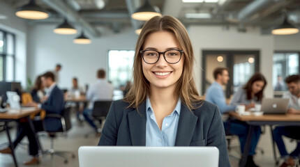 Young business people in office. professional and cheerful young woman smiling directly at the camera. She is seated in a modern, open-plan office