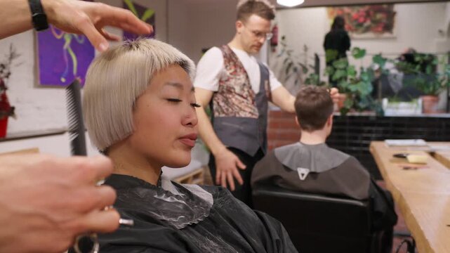 Hairdresser cutting blonde bob hairstyle in slow motion